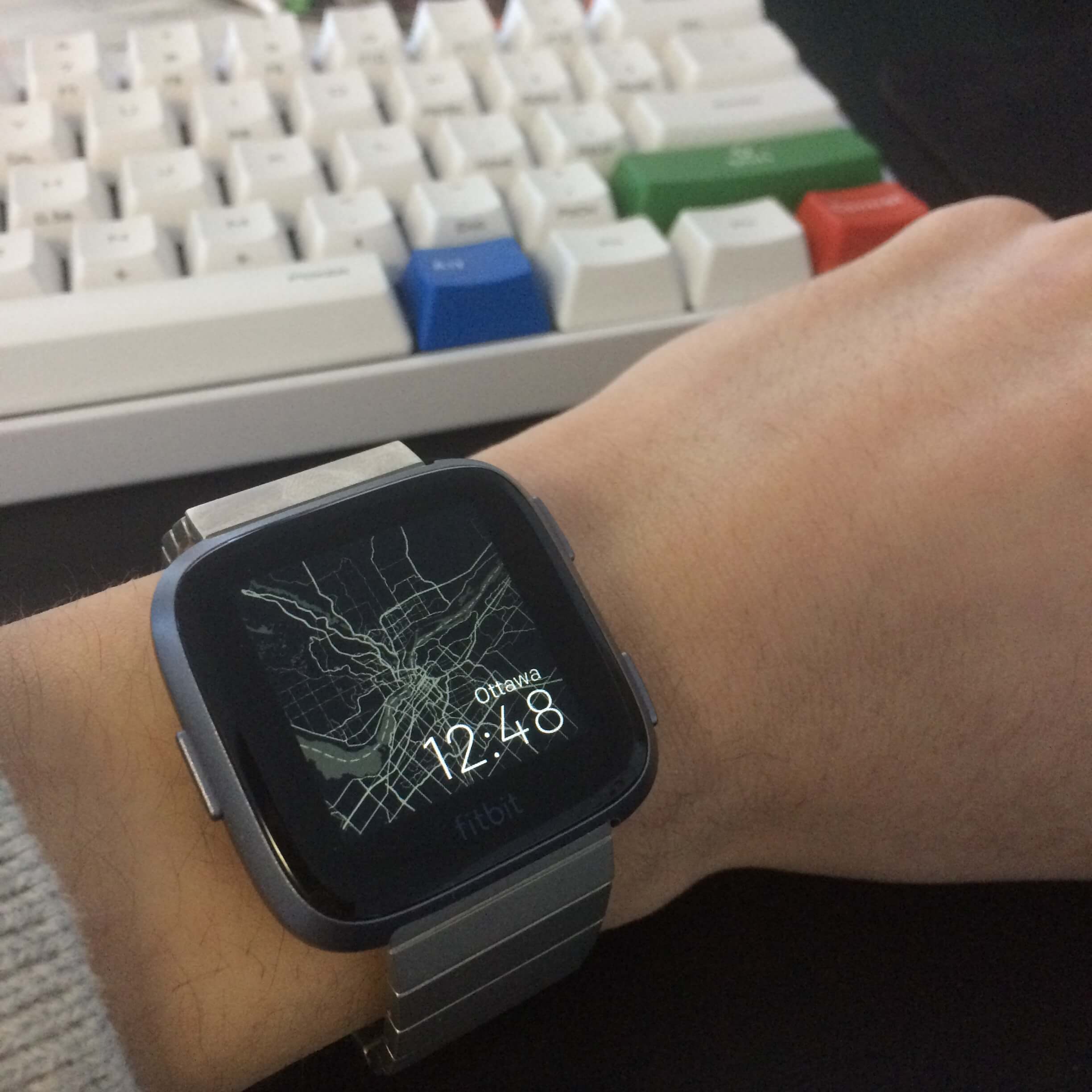 Fitbit Versa on wrist with Carta clock face